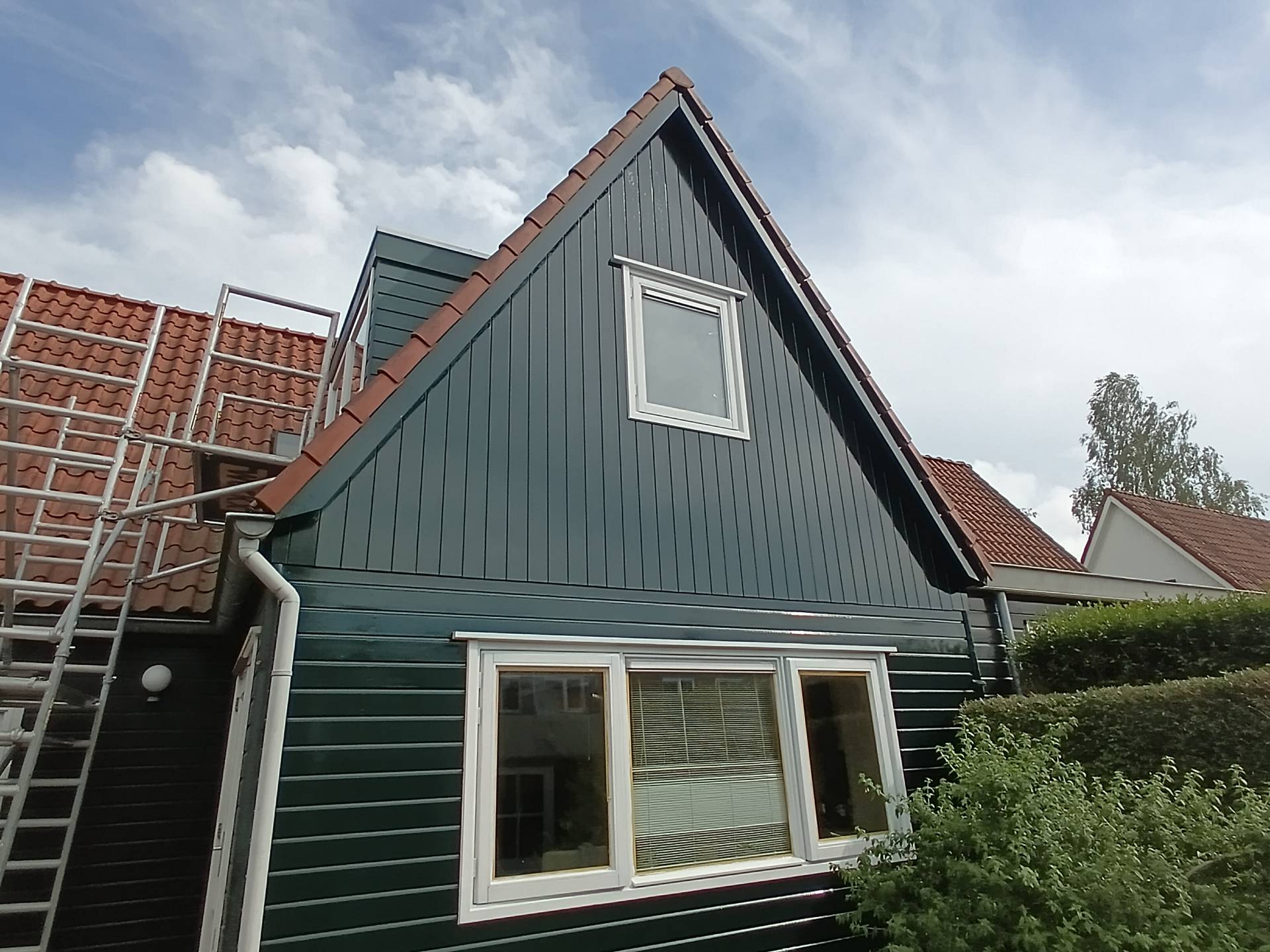 Houten topgevel in petrolgroen geschilderd met witte kozijnranden